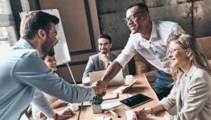 Group of colleagues shaking hands at desk